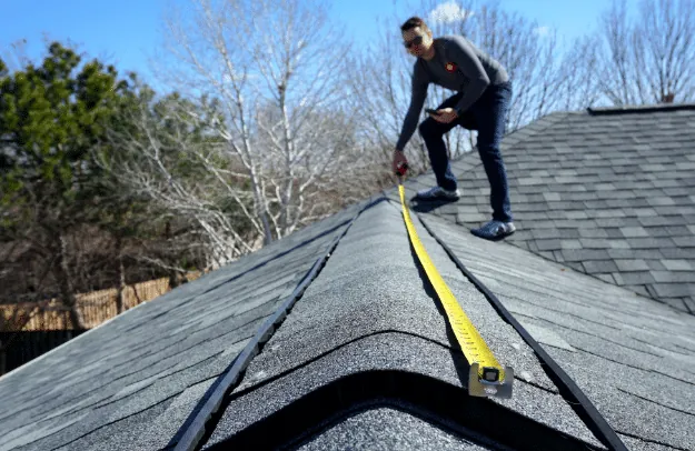 Inspector measuring the ridge line of a shingle roof